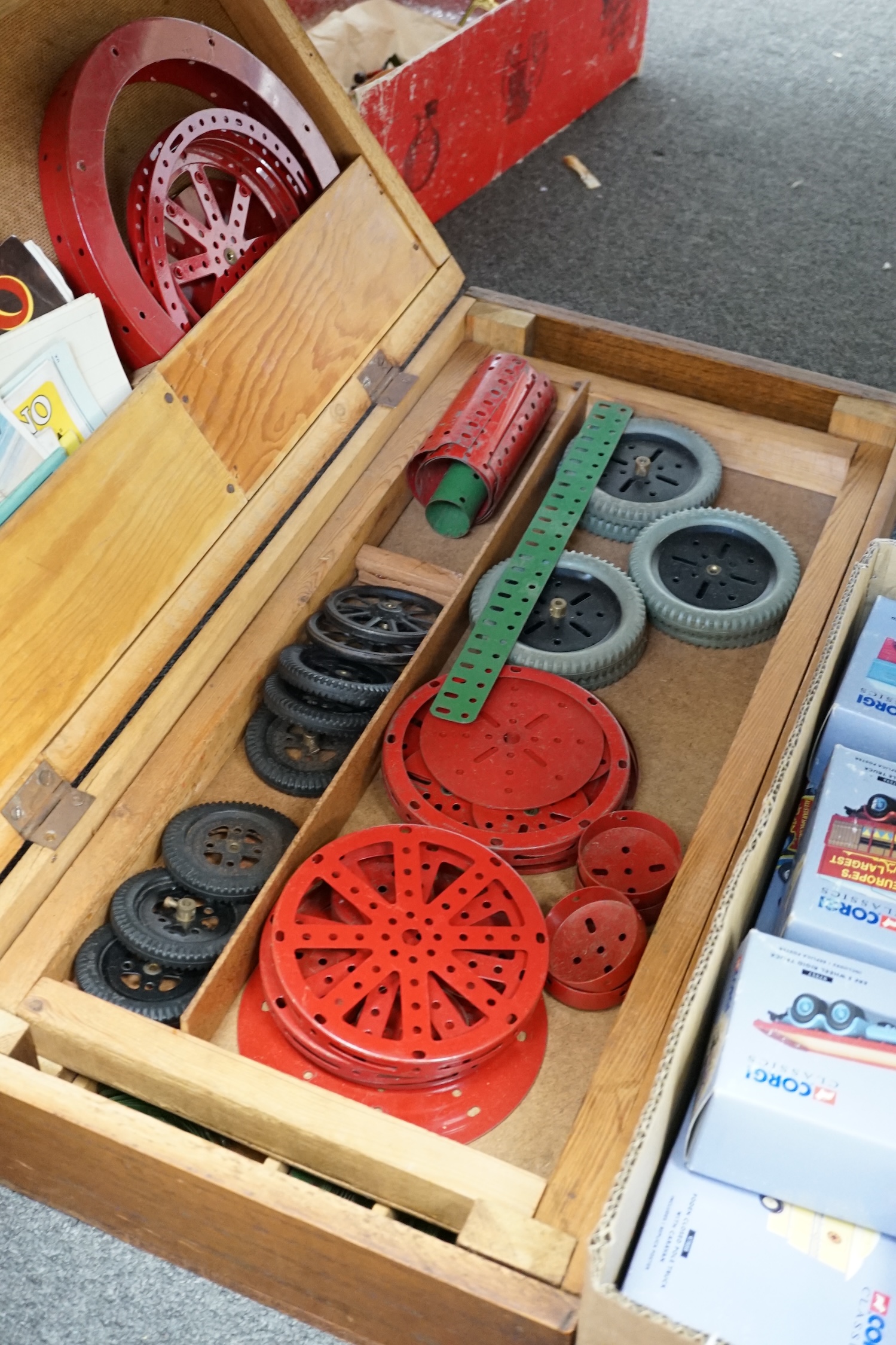 A collection of early Meccano components, mainly from the red and green period, comprising of some of the more unusual wheels and circular parts, some instruction books, etc. well organised into two wooden boxes